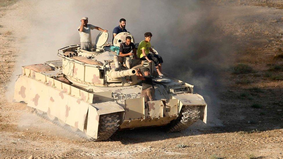 Syrian rebel fighters ride a tank in Deraa, south-western Syria, on 23 June 2018