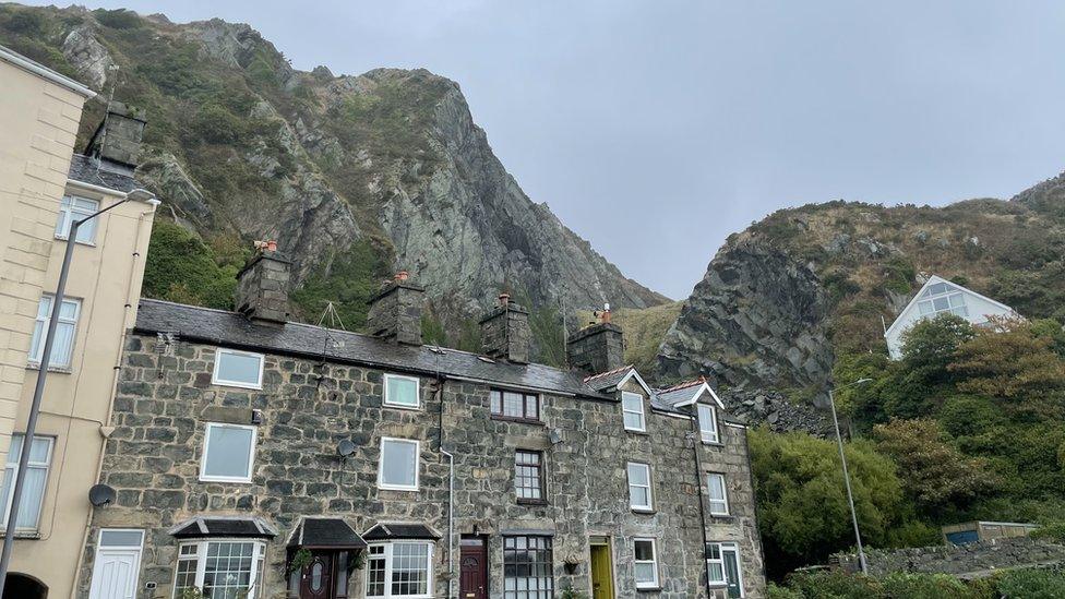 Old quarry face above stone buildling in Barmouth