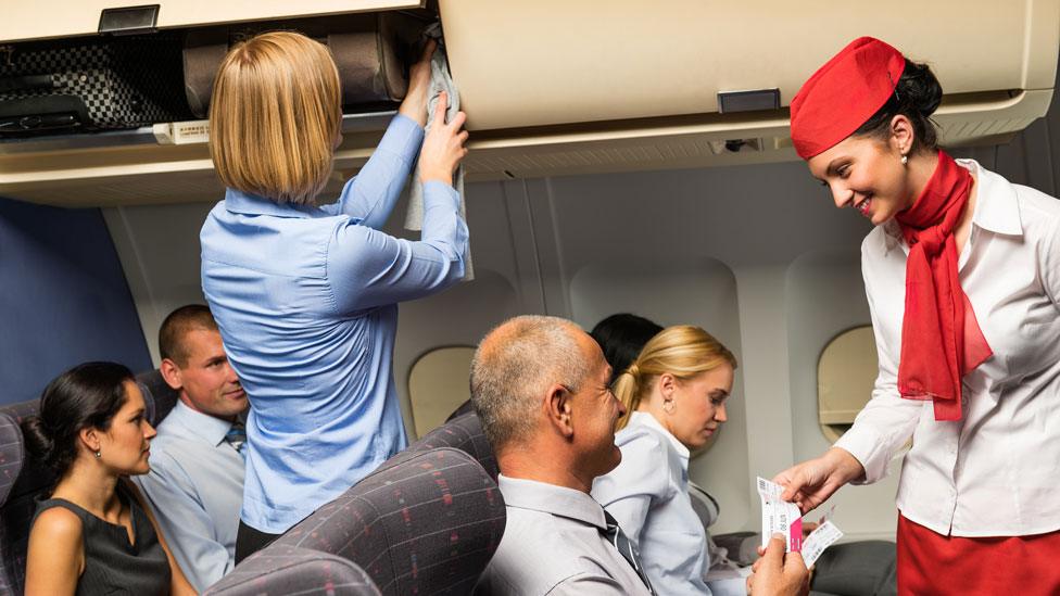 Passengers and air hostess, with one locker open and one closed