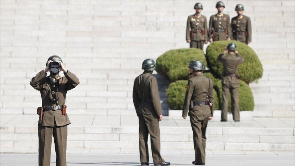 A North Korean soldier looks through binoculars towards South Korea