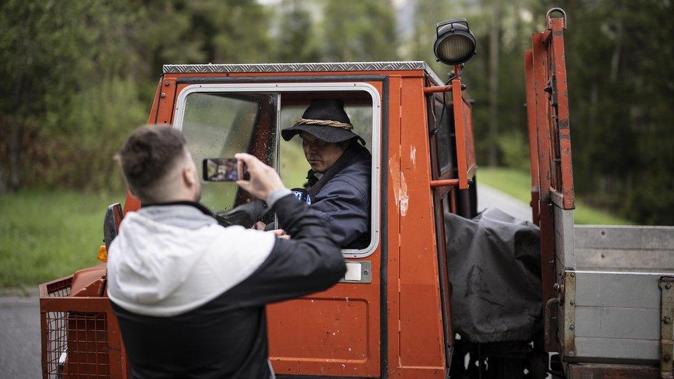 A man photographs Renato Liesch, a resident of Brienz/Brinzauls beneath the 'Brienzer Rutsch' who is driving away as the village is being evacuated