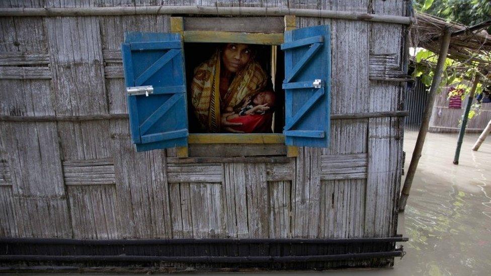 A woman holds her 41-day-old baby boy as she looks out from the window of her partially submerged house at Gagolmari village 85 kilometers (53 miles) east of Gauhati, India, Wednesday, Sept. 2, 2015