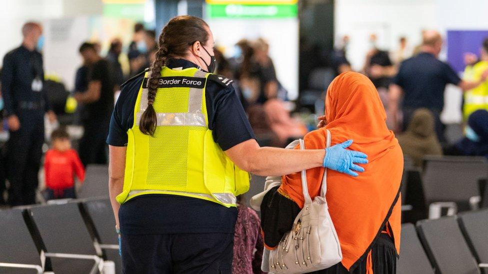 A Border Force officer helps a Afghan evacuee