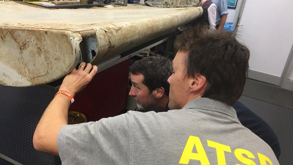 Australian Transport Safety Bureau (ATSB) staff examine a piece of aircraft debris at their laboratory in Canberra, Australia, July. 20, 2016.