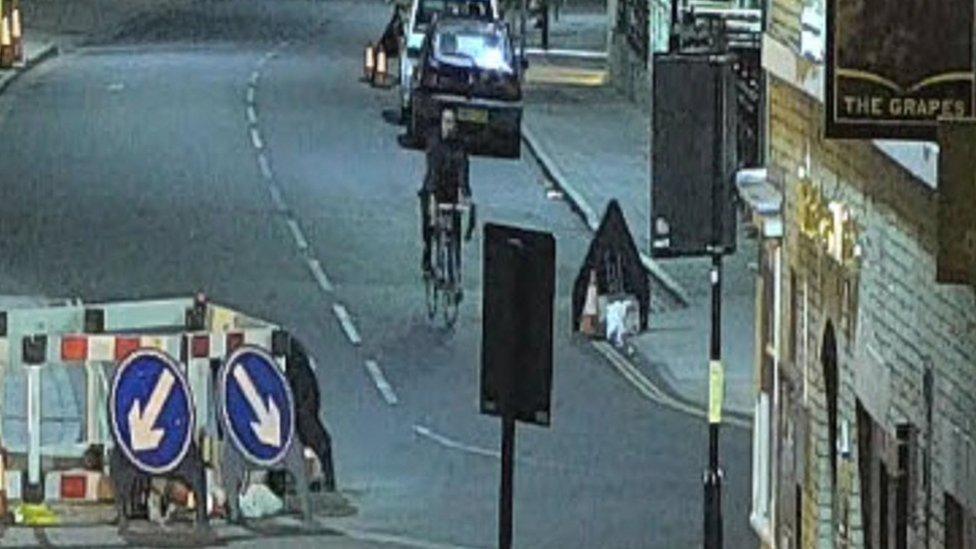 A person on a bicycle, thought to be male with short hair, wearing dark clothing. He was seen on CCTV cycling around the Cornhill area and is here captured in the area of The Grapes in Brentgovel Street.