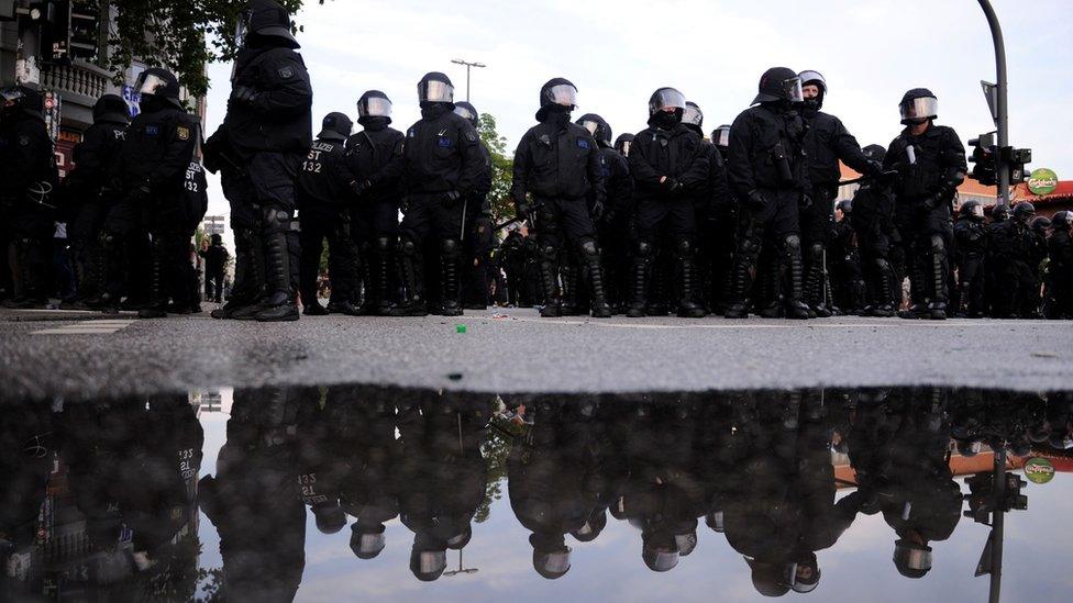 Riot police are reflected in water on July 7, 2017 in Hamburg, northern Germany,