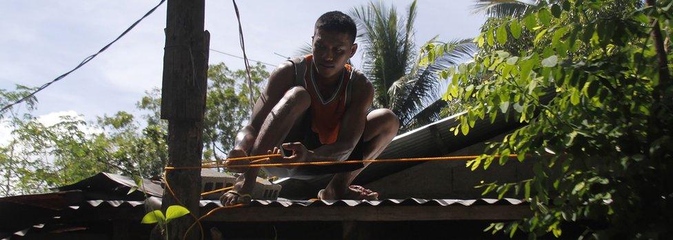 A resident secures the roof of his house to a tree in preparation for super typhoon Mangkhut in Candon City, Ilocos Sur province, north of Manila on September 13, 2018