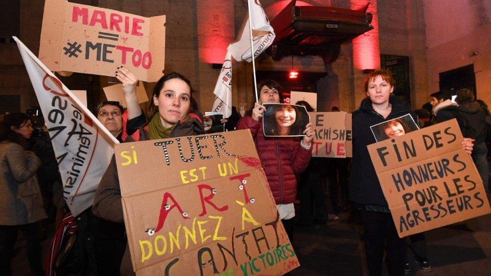 Women hold signs outside of concert venue with victim Marie Trintignant's face on it