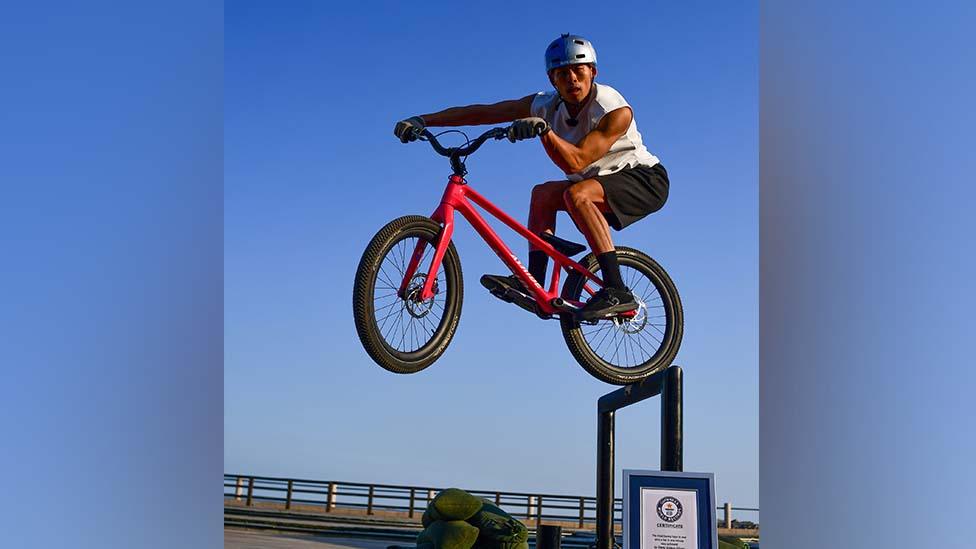 A cyclist performing a bunny hop to rear onto a bar in China