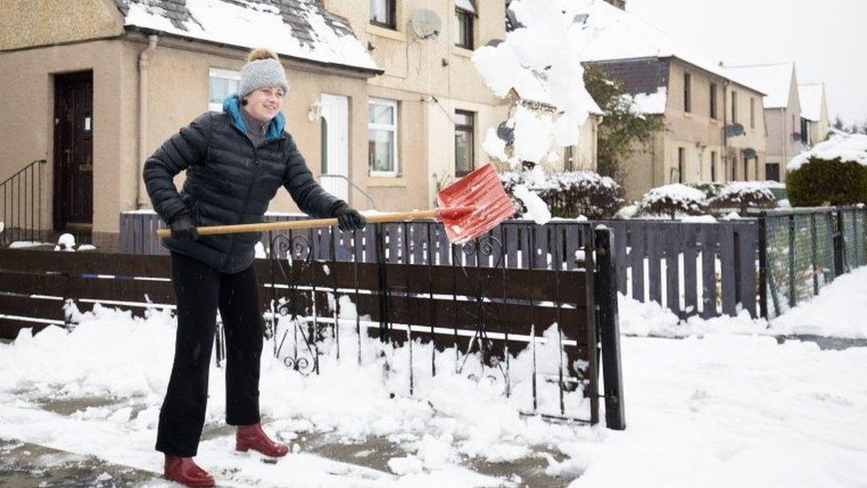 Kasia Wojcik clears snow from her driveway in Penicuik, Midlothian