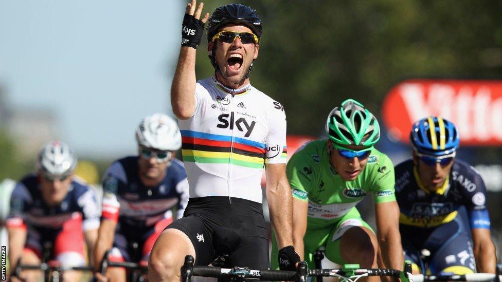 Mark Cavendish, wearing a Team Sky jersey, holds up his right hand as he crosses the line at the 2012 Tour de France