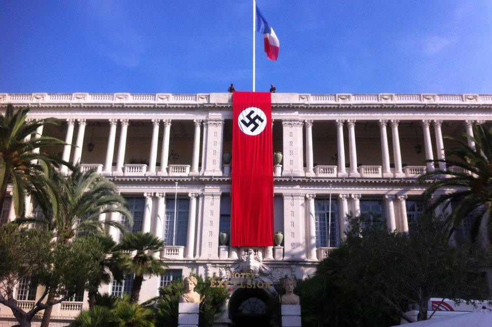 Two men hold Nazi banner over facade of the Palais de la Prefecture in Nice on Monday 28 September