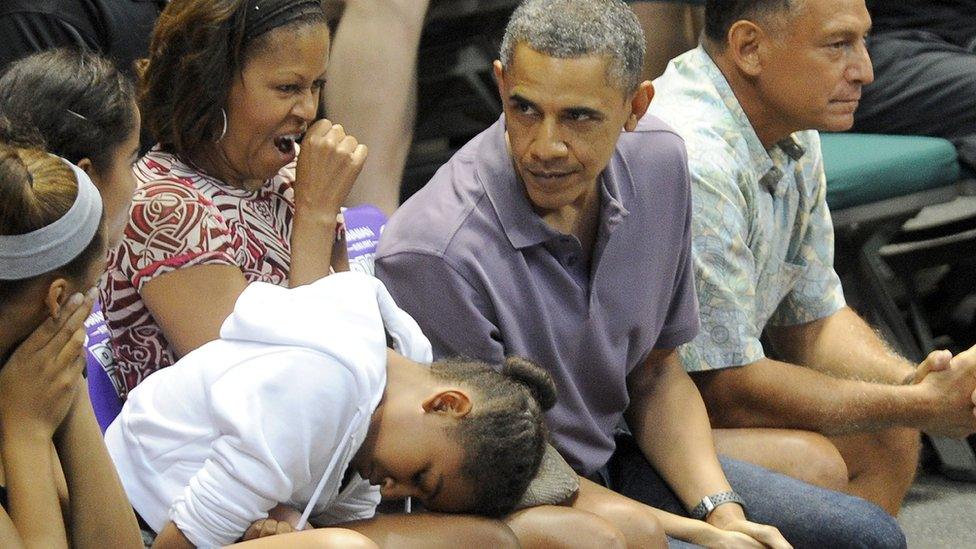 Sasha Obama rests her head on her knee as Michelle Obama yawns