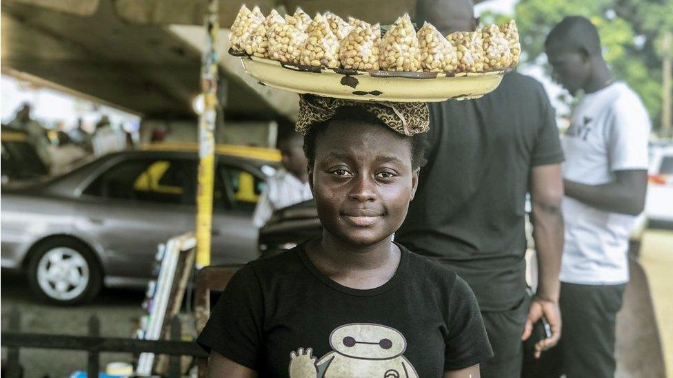 Street seller with a tray of groundnuts on her head