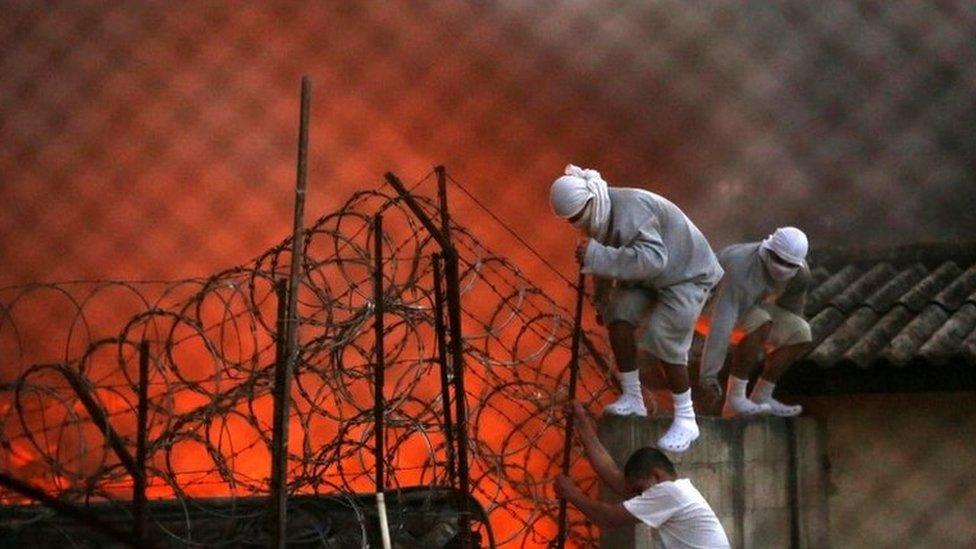 Inmates from a youth detention centre in Guatemala City climb a fence