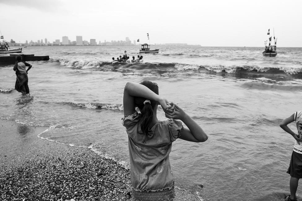 A girl looks at the ocean while standing on a beach in Mumbai