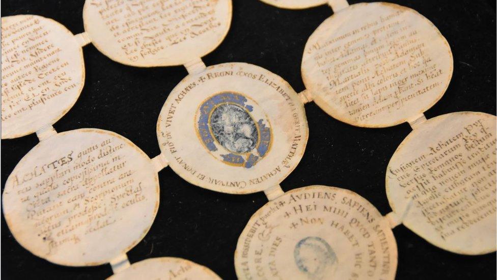 The roundels are one piece of paper made up of small circles joined by thin rectangles of paper. They show lots of faded writing and images of gems.