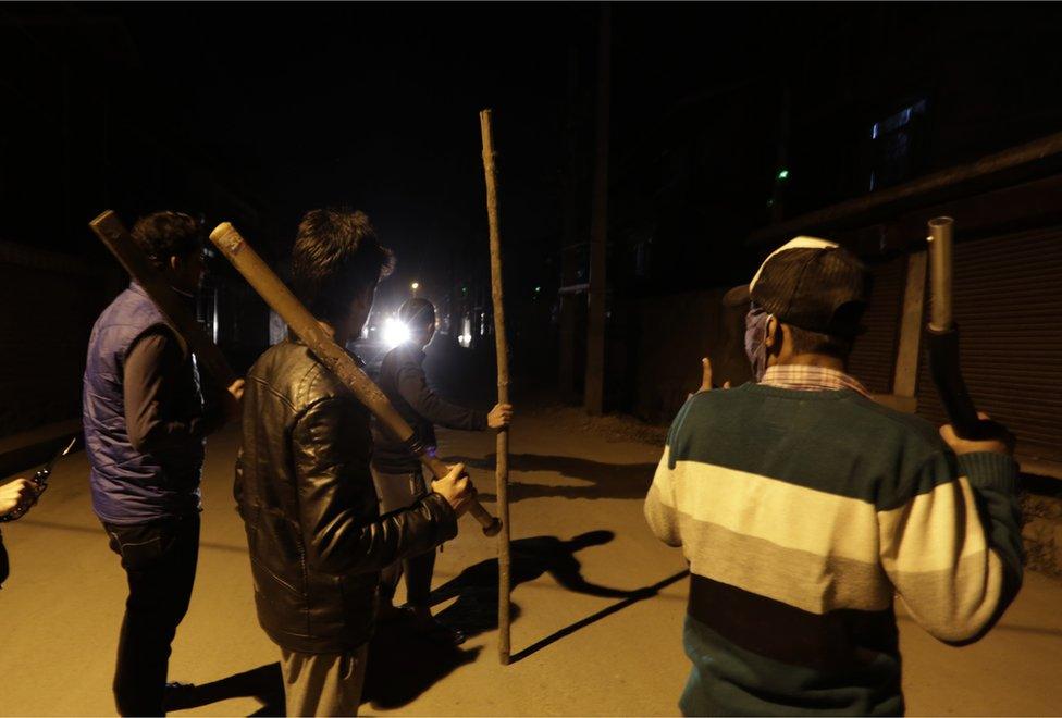 A group of Kashmiri men carry sticks and iron rods in a Srinagar neighbourhood while on the look out for "braid choppers"