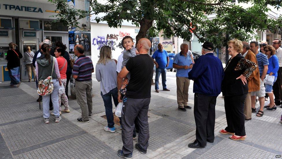 People stand in a queue to use ATM machines at a bank in Thessaloniki on 27 June 2015.