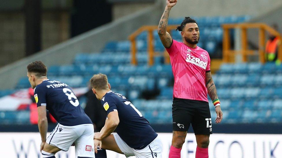 Derby County's Colin Kazim-Richards raises his fist as Millwall players take a knee