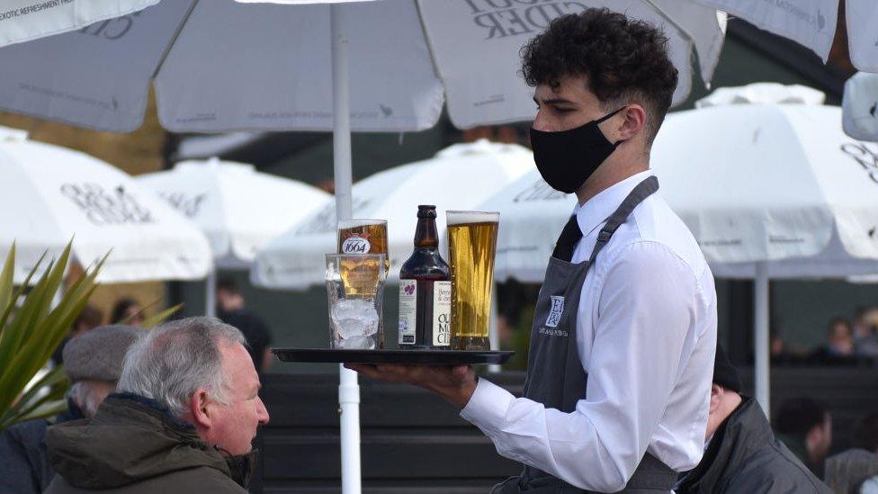 Waiter in mask serves drinks