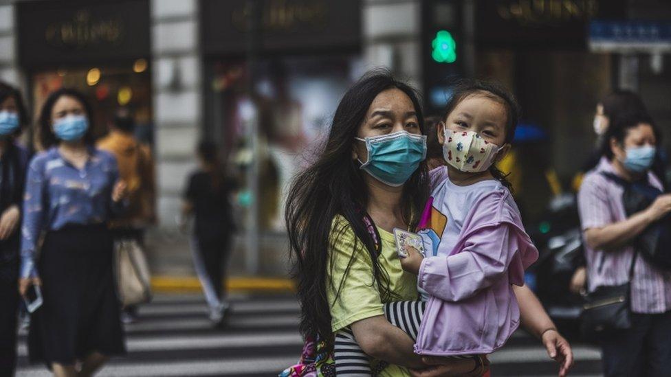 People cross the street in Shanghai, China, 11 May 2021