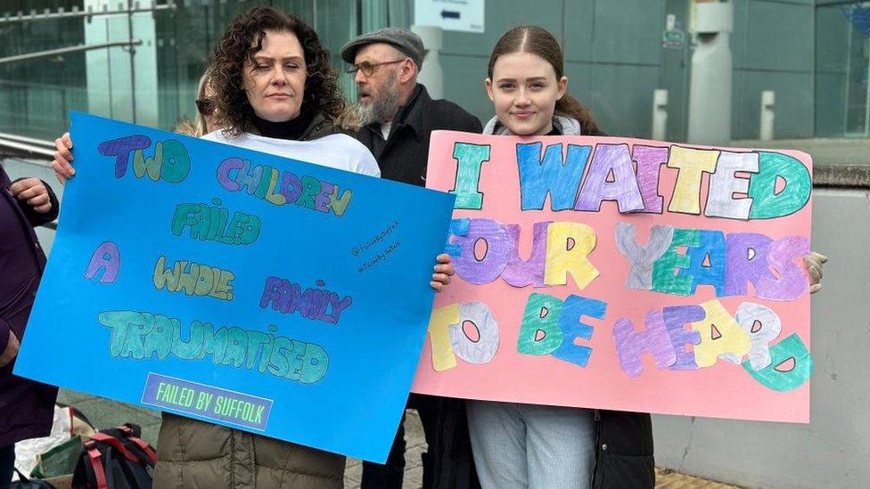 Two protesters holding up placards during the protest outside Suffolk County Council's Endeavour House in Ipswich