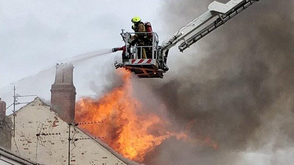 Firefighter putting out a fire in the roof of a hotel building