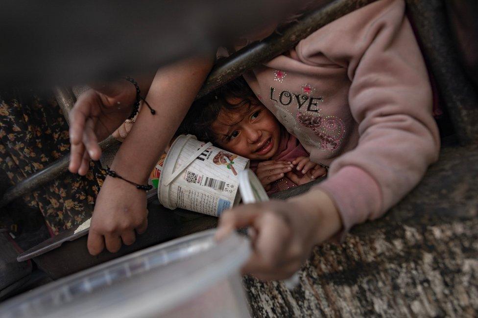 Palestinian children queue for food at an aid station in Gaza