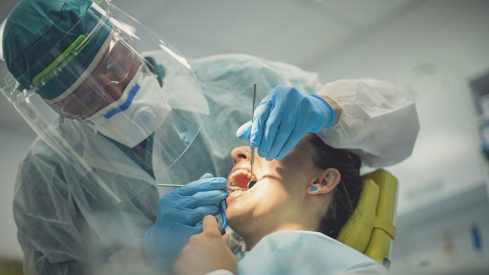 A dentist in PPE treating a patient