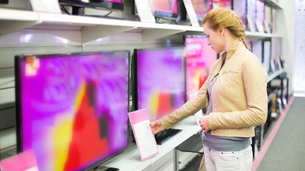 A woman looking at flat-screen TVs