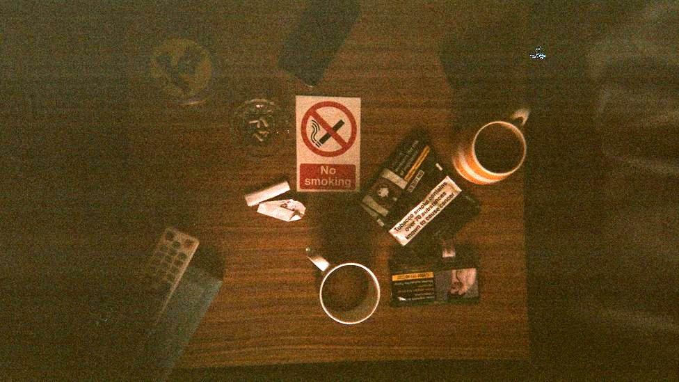 A birds-eye view of a table with mugs and cigarettes on it