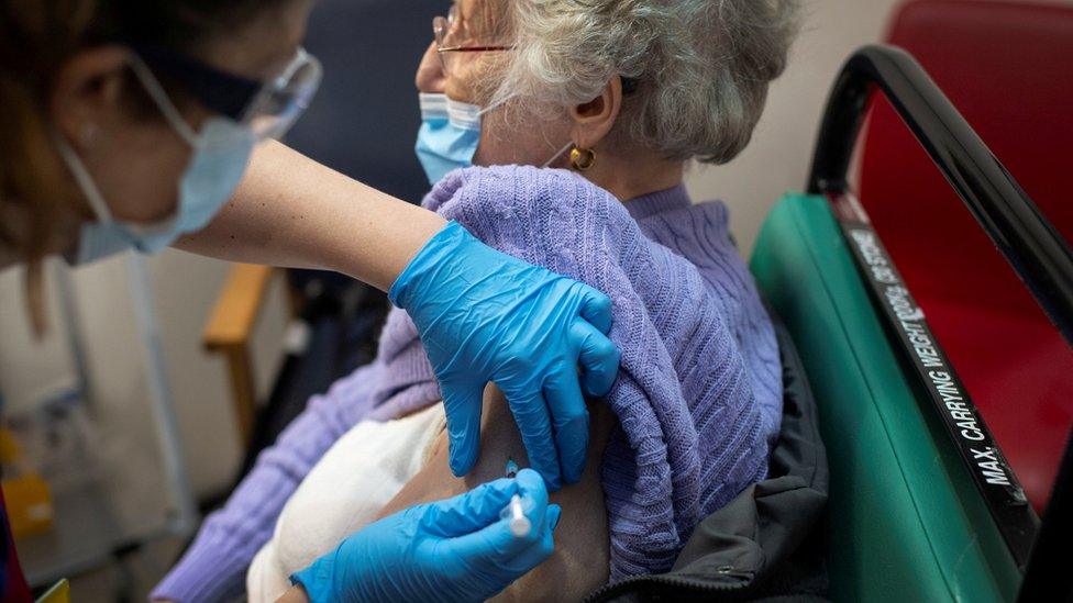 A woman receives the first of two Pfizer/BioNTech COVID-19 vaccine jabs, at Guy"s Hospital