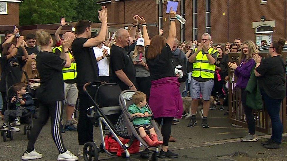 Crowd raise arms at the start of the walk