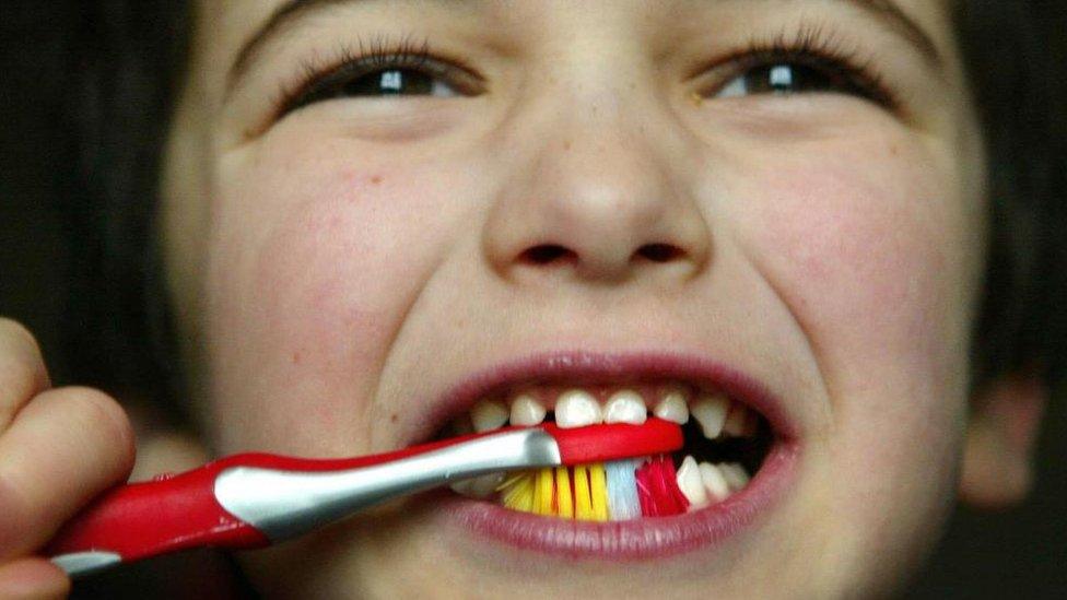 A stock image shows a young boy brushing his teeth