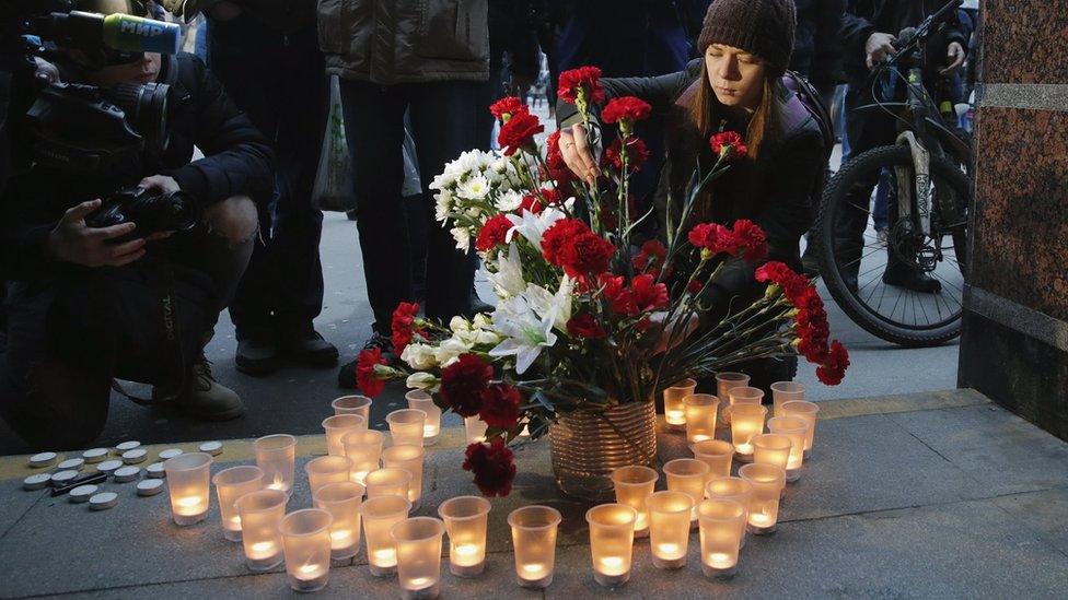 People light candles and lay flowers outside Sennaya Ploshchad metro station after an explosion, in St Petersburg, Russia, 3 April 2017