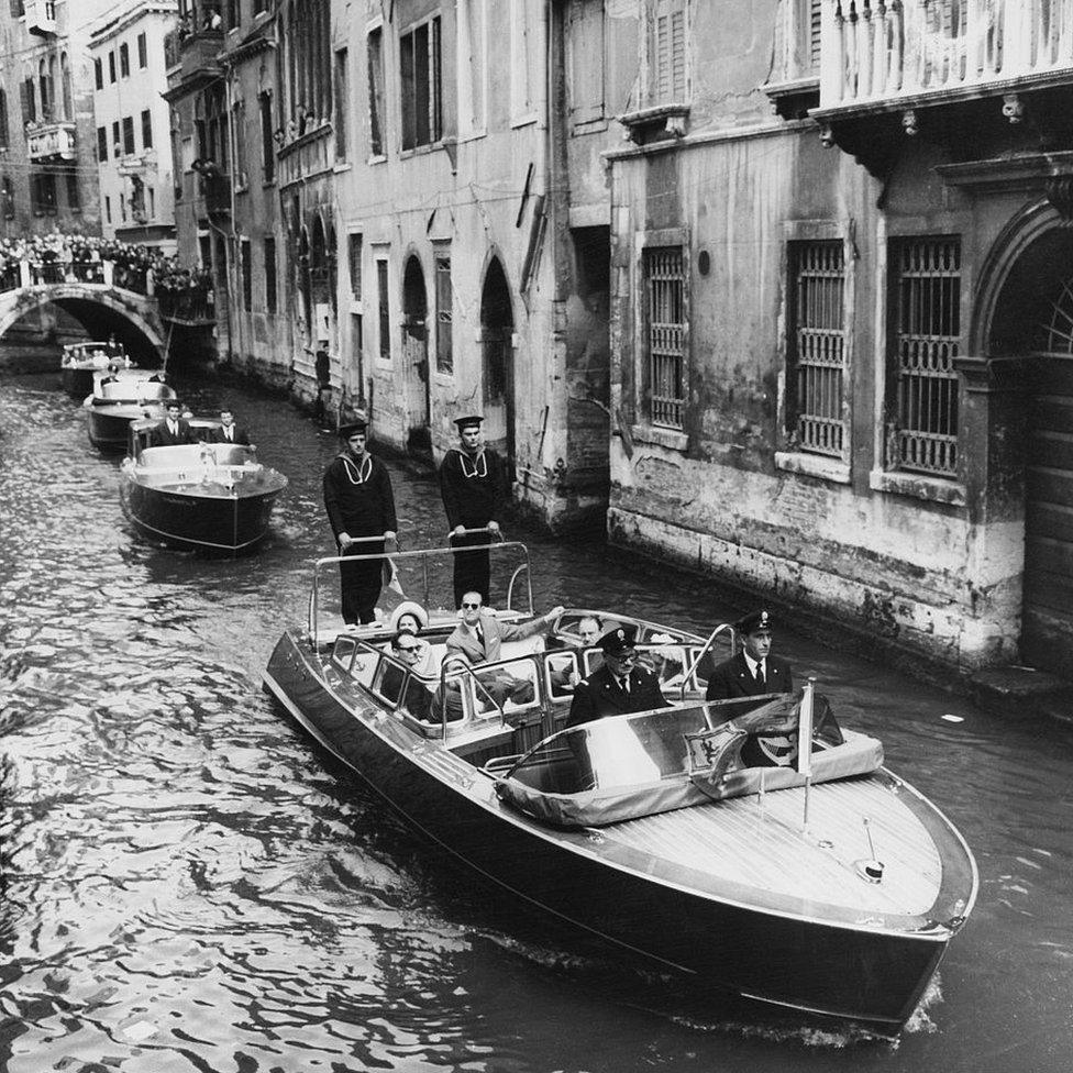 Queen Elizabeth II and Prince Philip, Duke of Edinburgh sit together in the rear seat of a motor boat as they take a cruise down a canal in Venice on the 3rd day of a State Visit to Italy on 4 May 1961.