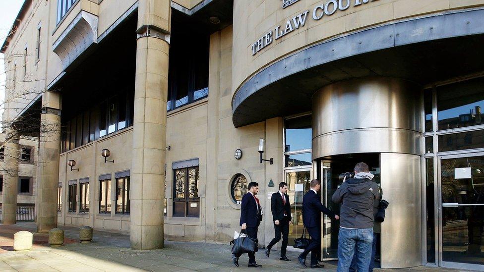 Footballer Adam Johnson (centre of group of three entering door) arrives with unidentified men at Bradford Crown Court for the start of the defence at his trial