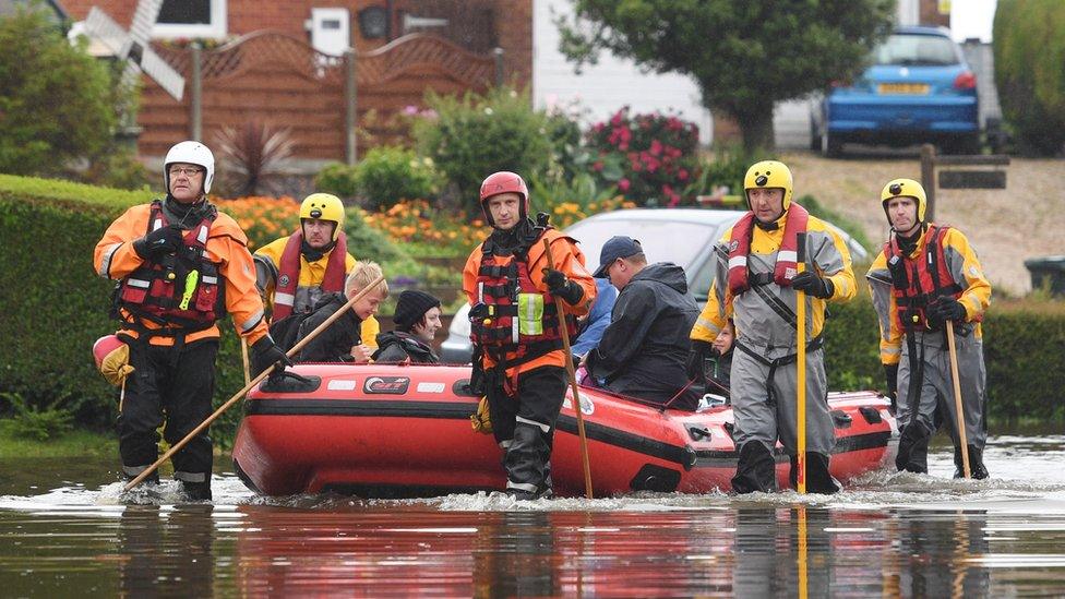 Residents are taken to safety in an inflatable boat by rescue workers in Wainfleet