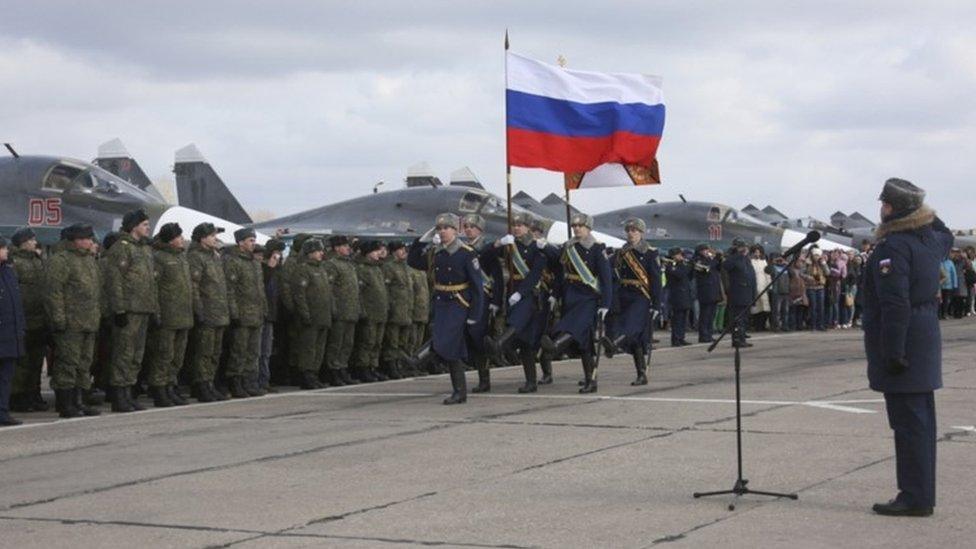 Guards walk past a line-up of troops during a welcome ceremony for Russian military personnel who returned from Syria at an airbase near the Russian city Voronezh (15 March 2016)