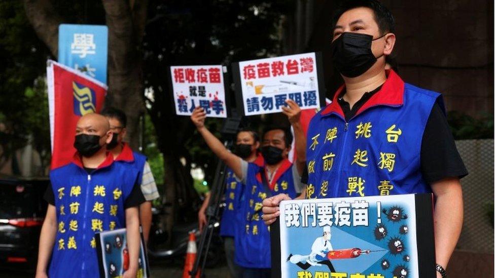 People hold placards calling for Taiwan government to allow the use of COVID-19 vaccines from China, in front of the Taiwan Centers for Disease Control building, following the recent spike in coronavirus disease infections in Taipei, Taiwan, May 24, 2021.