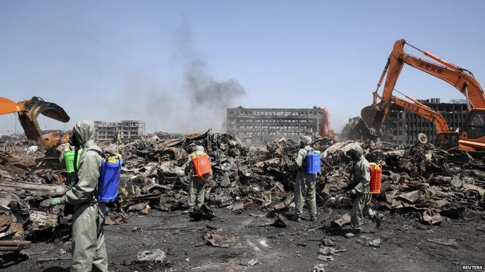 Chinese soldiers work next to excavators cleaning up the debris at the site of last wee's blasts in Binhai new district of Tianjin (21 August 2015)