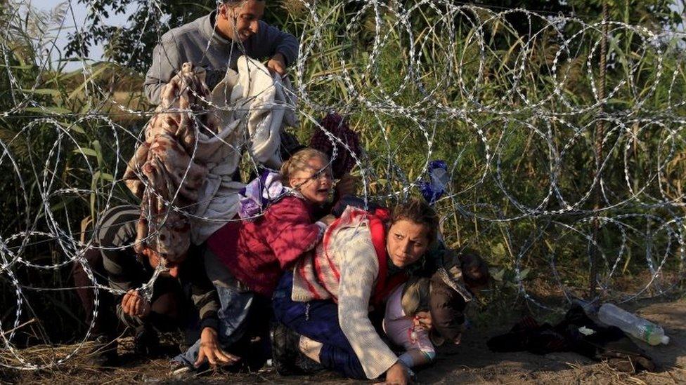 Migrants cross under a border fence as they enter Hungary from Serbia (image from August 2015)