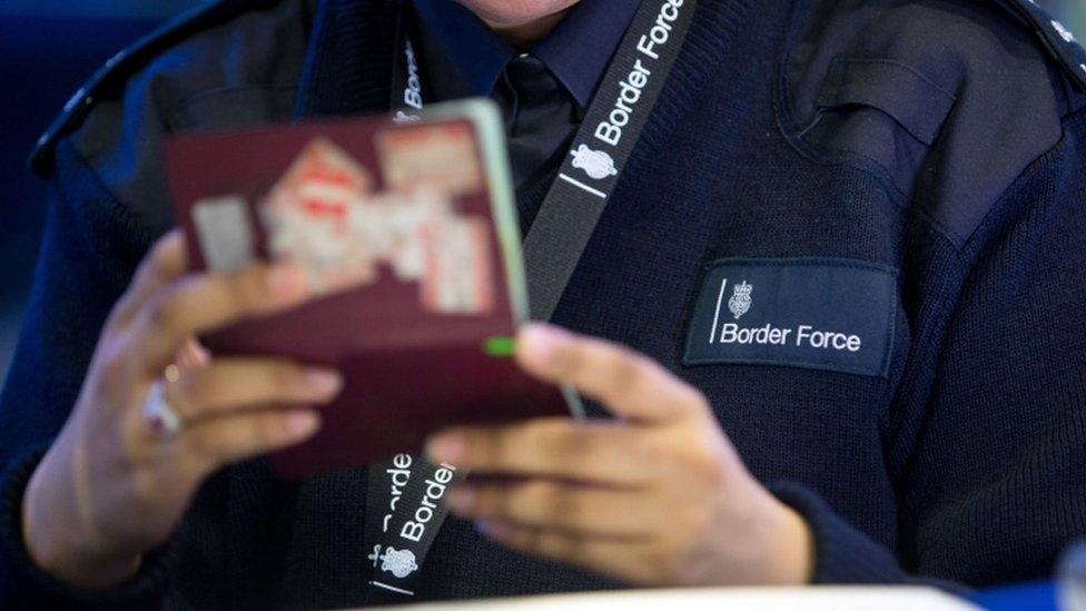 UK Border Force agent checks a passport