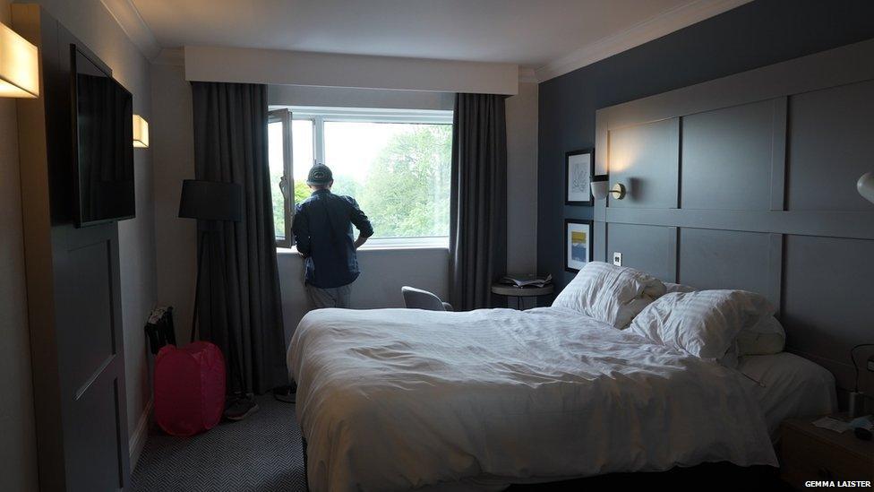 An anonymous man stares out of a hotel window