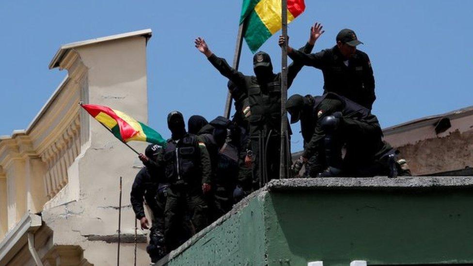 Police officers flying flags on the roof of a police station in La Paz on Saturday