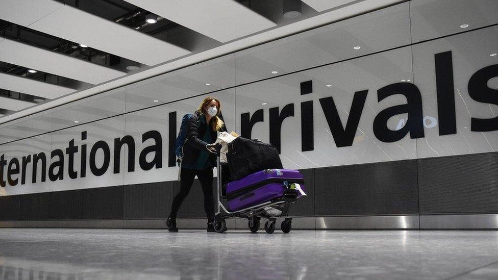 A passenger pushes luggage through the Arrival Hall of Terminal 5 at London"s Heathrow Airport