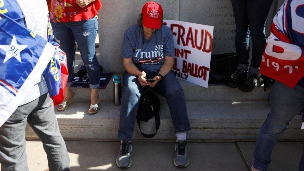 A Trump supporter sits on the floor