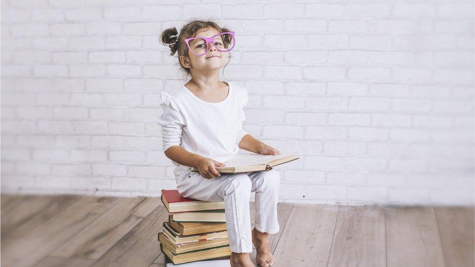 girl-glasses-sat-on-books.