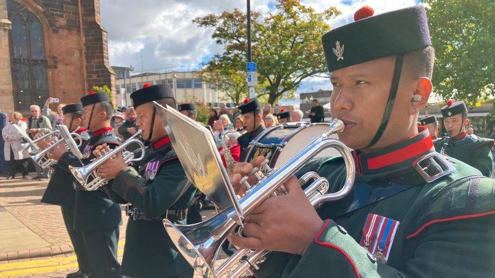 soldiers on parade in a street blowing trumpets